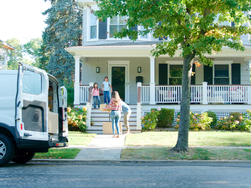 Family moving boxes into house